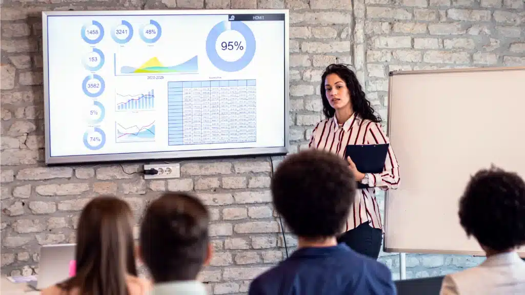 Profissional apresentando gráficos, dados e tabelas em um slide, representando o uso de storytelling com dados em apresentações corporativas.