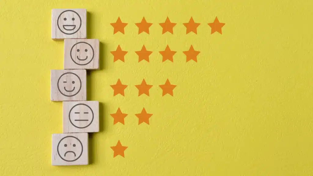 Blocos de madeira com emojis de diferentes expressões e estrelas de 1 a 5, representando a avaliação da eficácia de um treinamento corporativo.