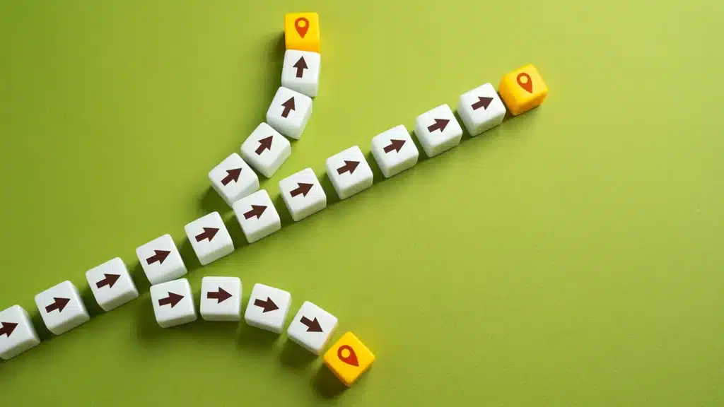 Cubos formando diferentes caminhos com setas e ícones de destino, simbolizando o design instrucional e as trilhas de aprendizagem no T&D.