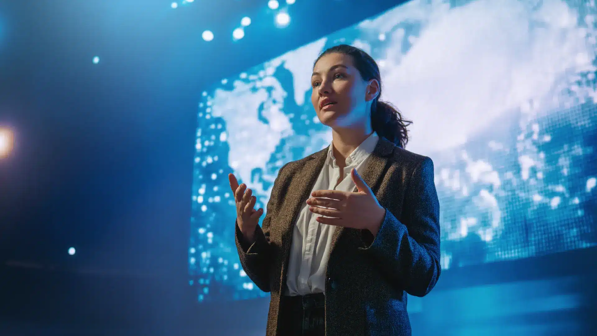 Mulher apresentando com segurança diante de uma tela iluminada, ilustrando o uso de narrativas em apresentações corporativas.